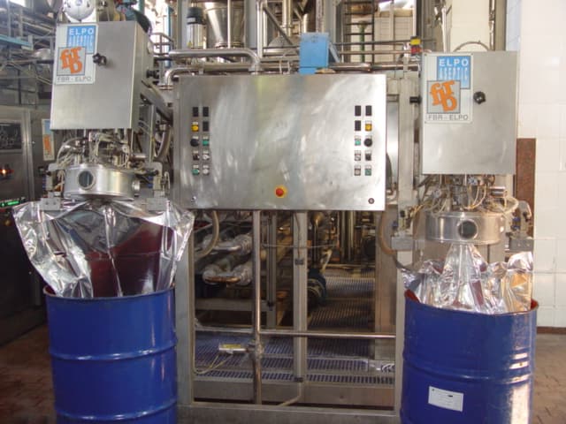 Aseptic filling station with foil bags being filled inside blue steel drums beside a stainless steel control cabinet